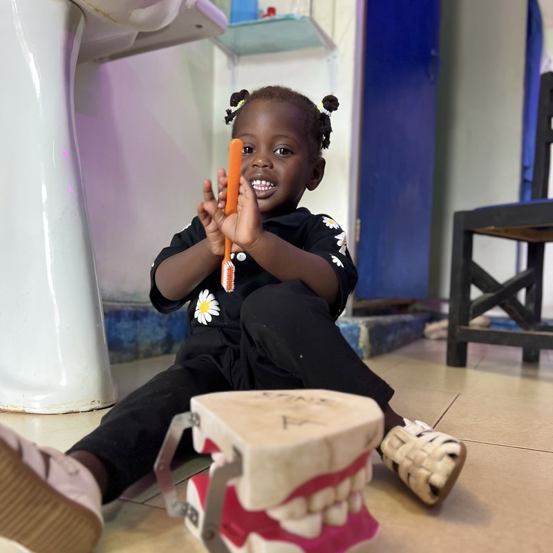 Young patient smiling with toothbrush at Piwan Dental pediatric clinic, Gulu