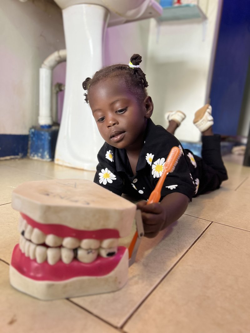 Young child learning about dental care at Piwan Dental's pediatric clinic in Gulu